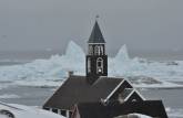 Zion Church, verdadeiro cartão postal de Ilulissat, na Groelândia. Ao fundo, icebergs passam pela costa.